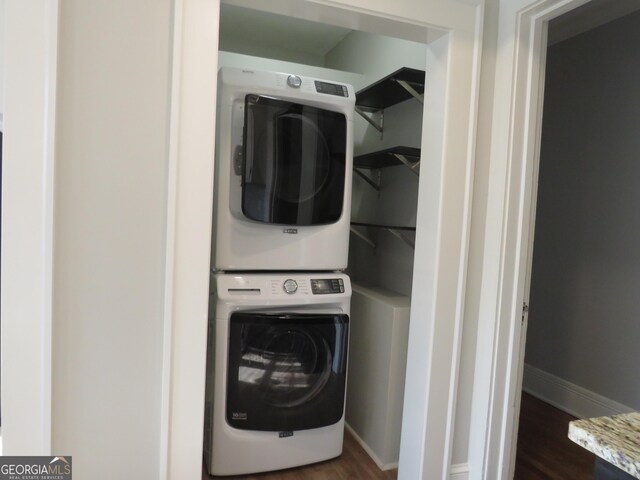 washroom with stacked washer / drying machine and dark wood-type flooring