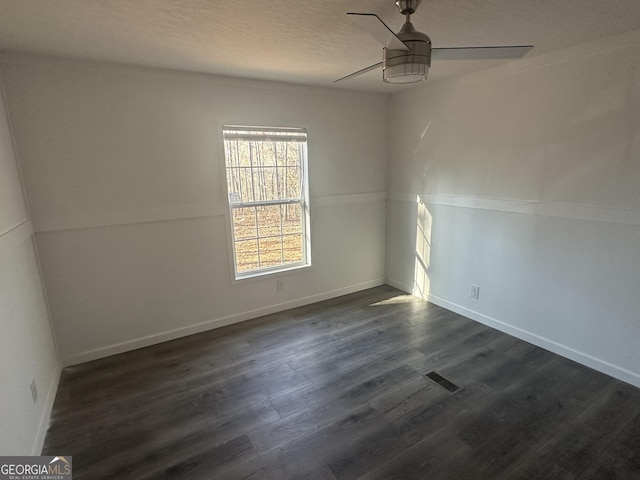 empty room featuring ceiling fan, dark wood-type flooring, and a textured ceiling