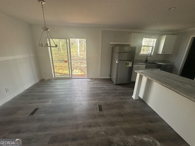 unfurnished dining area with a textured ceiling, sink, a chandelier, and dark hardwood / wood-style floors