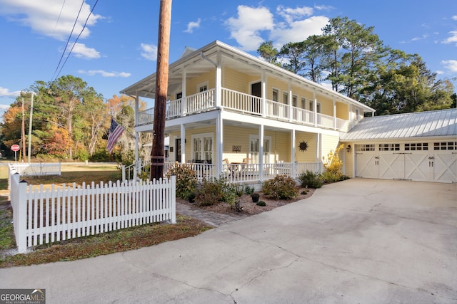 view of property featuring covered porch, a garage, a balcony, and an outdoor structure