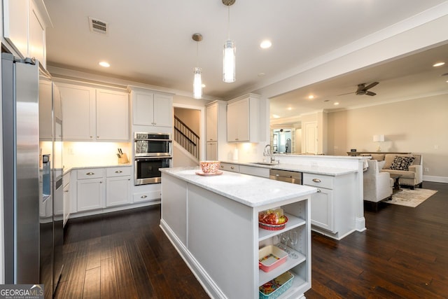 1560 Tapestry Rdg, Lawrenceville, GA 30045 - kitchen featuring stainless steel appliances, a peninsula, dark wood-style floors, ornamental molding, and white cabinetry