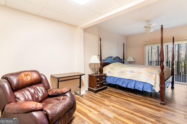 bedroom featuring light wood-style flooring, a paneled ceiling, baseboards, and ceiling fan