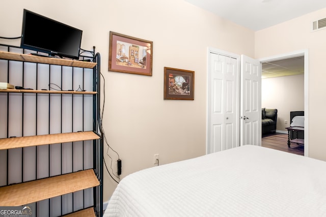 bedroom featuring a drop ceiling, a closet, visible vents, and wood finished floors