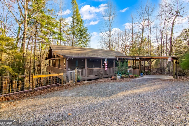 rustic home with gravel driveway, fence, and a shingled roof