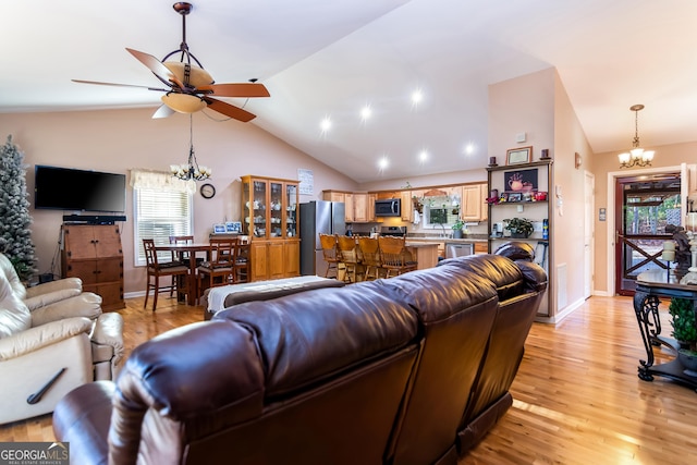 living room with high vaulted ceiling, light wood-style flooring, and ceiling fan with notable chandelier