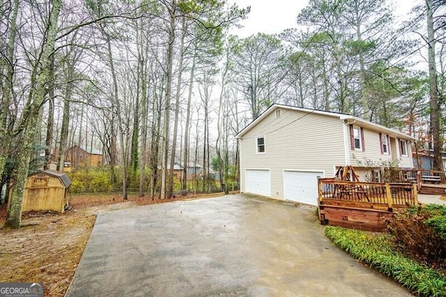 view of property exterior with a garage, a deck, and a storage unit