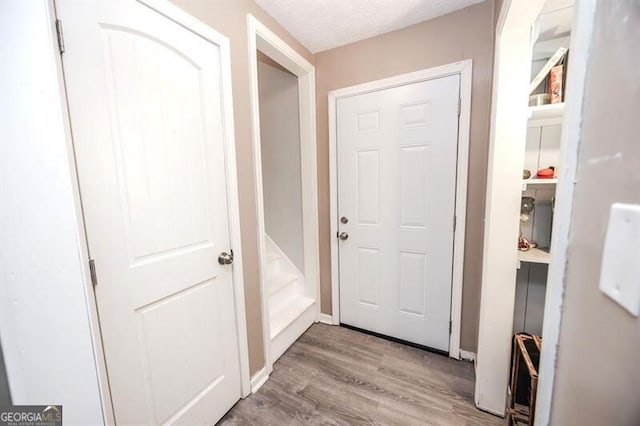 corridor with a textured ceiling and light wood-type flooring