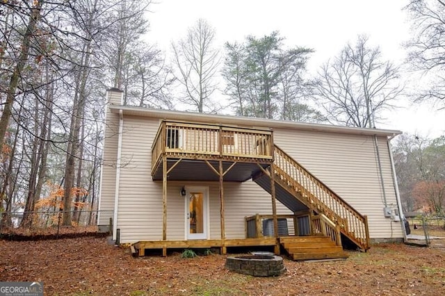 back of house with a wooden deck and an outdoor fire pit