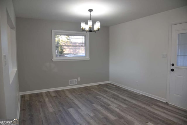 empty room with a chandelier and dark hardwood / wood-style floors