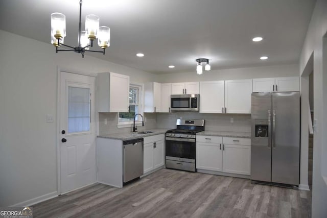 kitchen featuring pendant lighting, white cabinets, sink, appliances with stainless steel finishes, and light hardwood / wood-style floors