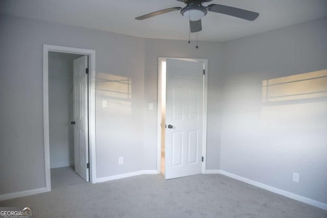 unfurnished bedroom featuring light carpet, a closet, ceiling fan, and a spacious closet