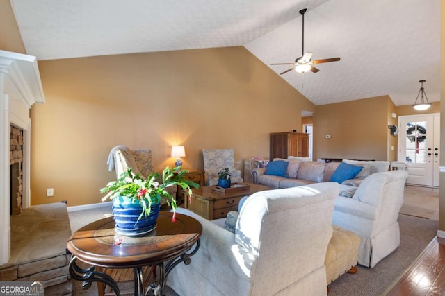 living room featuring ceiling fan, lofted ceiling, a stone fireplace, and hardwood / wood-style floors