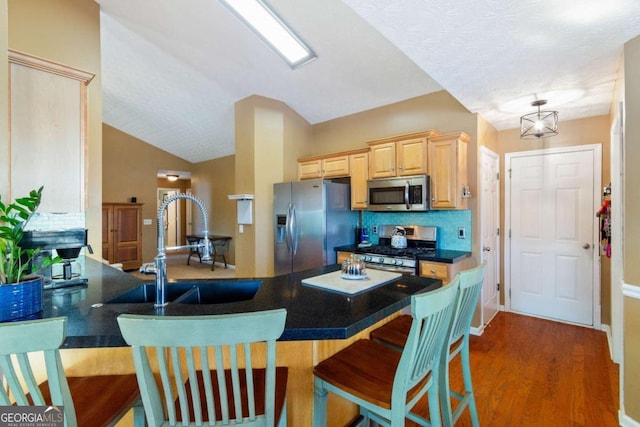 kitchen with tasteful backsplash, appliances with stainless steel finishes, kitchen peninsula, and sink