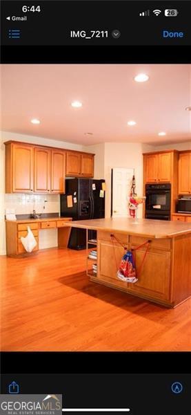 kitchen with light hardwood / wood-style flooring and black appliances