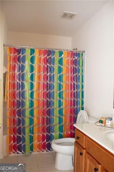 full bathroom with tile patterned flooring, vanity, toilet, and shower / bath combo with shower curtain