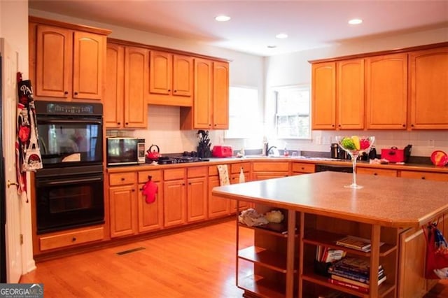 kitchen with sink, decorative backsplash, light wood-type flooring, a kitchen island, and stainless steel appliances