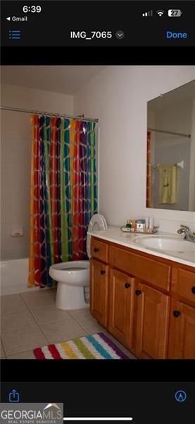 full bathroom featuring tile patterned floors, vanity, toilet, and shower / tub combo with curtain