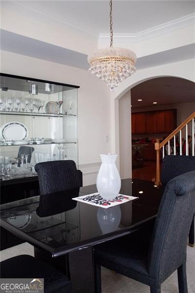 dining space featuring carpet, a chandelier, and ornamental molding