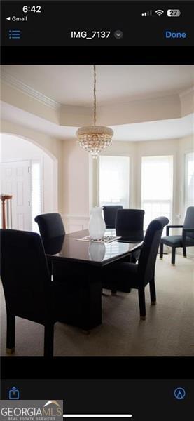 carpeted dining space featuring crown molding and a notable chandelier