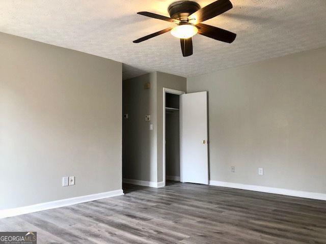 unfurnished room with ceiling fan, a textured ceiling, and hardwood / wood-style flooring