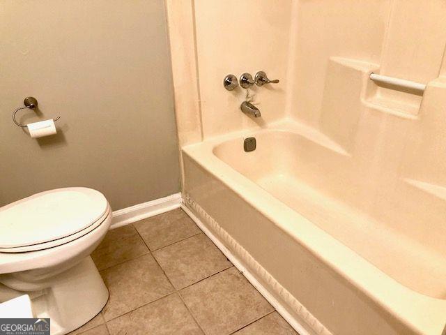 bathroom with tile patterned flooring, toilet, and washtub / shower combination