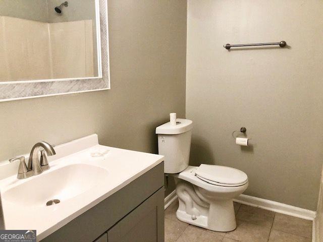 bathroom with toilet, vanity, and tile patterned floors