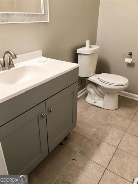 bathroom with tile patterned flooring, vanity, and toilet