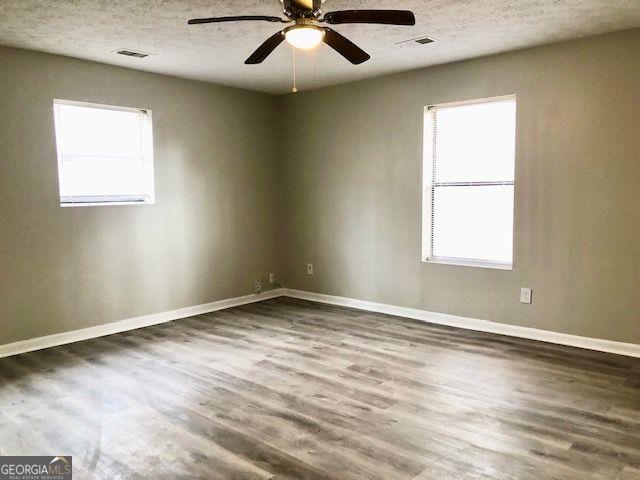 spare room with ceiling fan, wood-type flooring, and a wealth of natural light