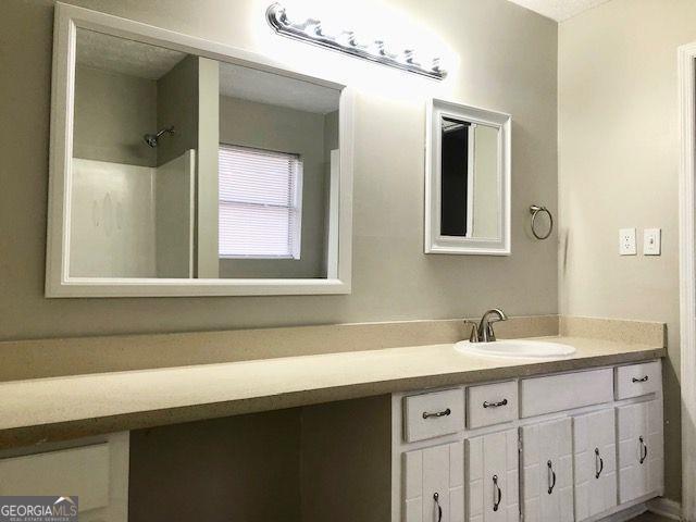 bathroom featuring a shower and vanity