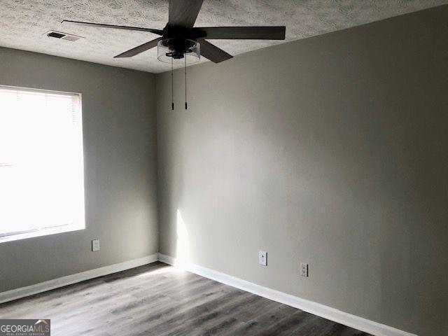 spare room featuring a textured ceiling, hardwood / wood-style flooring, and ceiling fan