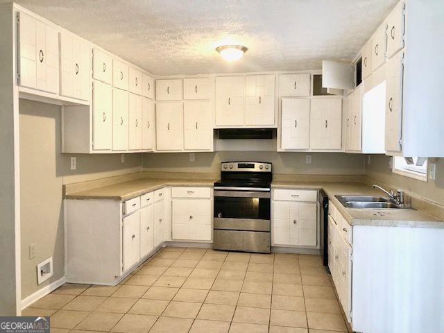 kitchen with sink, light tile patterned floors, electric range, white cabinets, and black dishwasher