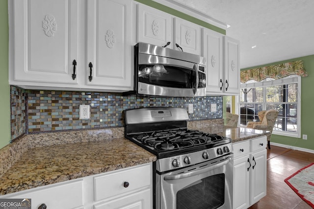 kitchen with backsplash, white cabinetry, stainless steel appliances, and stone countertops