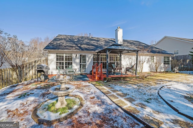 snow covered rear of property with a gazebo and a wooden deck