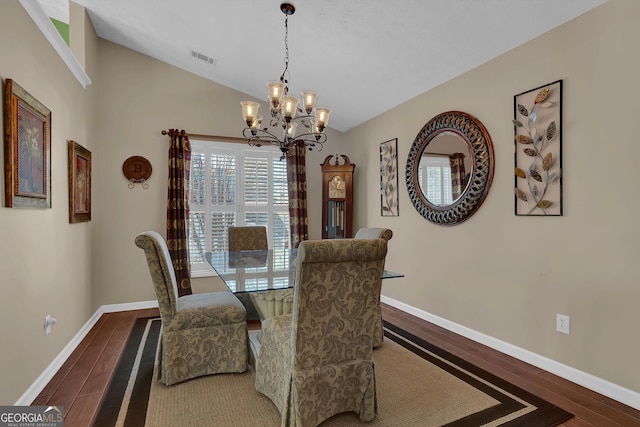 dining space featuring a notable chandelier, dark hardwood / wood-style floors, and lofted ceiling