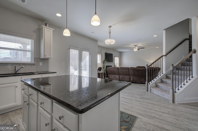 kitchen featuring white cabinetry, sink, hanging light fixtures, and a center island