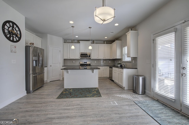 kitchen with hanging light fixtures, appliances with stainless steel finishes, sink, and white cabinets