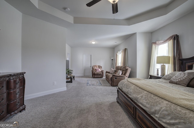 bedroom featuring ceiling fan, light colored carpet, and a tray ceiling