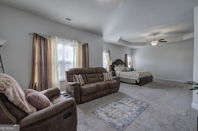 bedroom with a raised ceiling, carpet floors, and ceiling fan