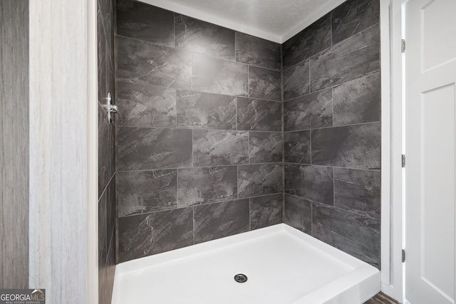 bathroom with tiled shower and a textured ceiling