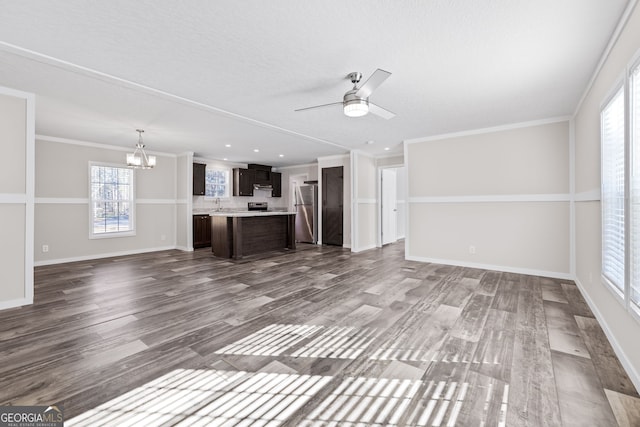 unfurnished living room with ceiling fan with notable chandelier, hardwood / wood-style flooring, and crown molding