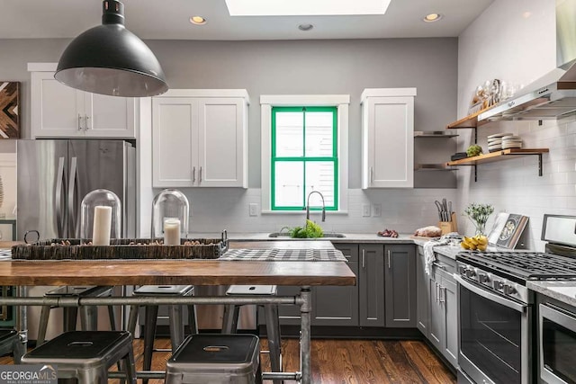 kitchen featuring sink, wall chimney exhaust hood, stainless steel appliances, gray cabinets, and white cabinets