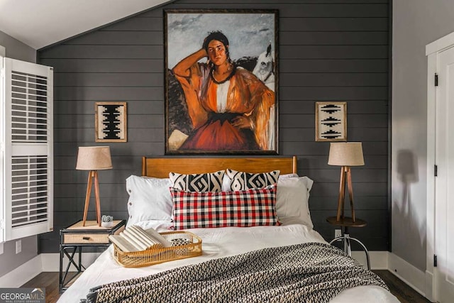 bedroom featuring hardwood / wood-style floors, wood walls, and lofted ceiling