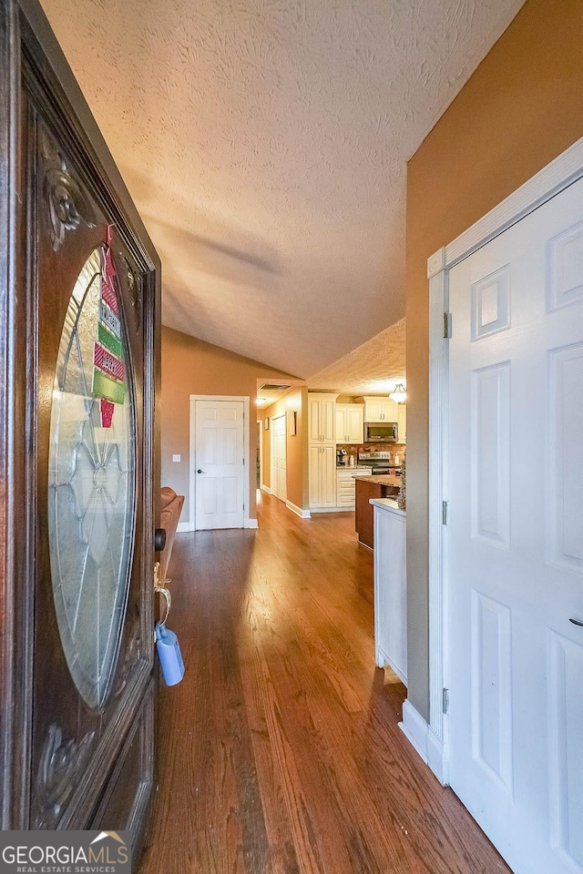 corridor featuring vaulted ceiling, dark hardwood / wood-style floors, and a textured ceiling