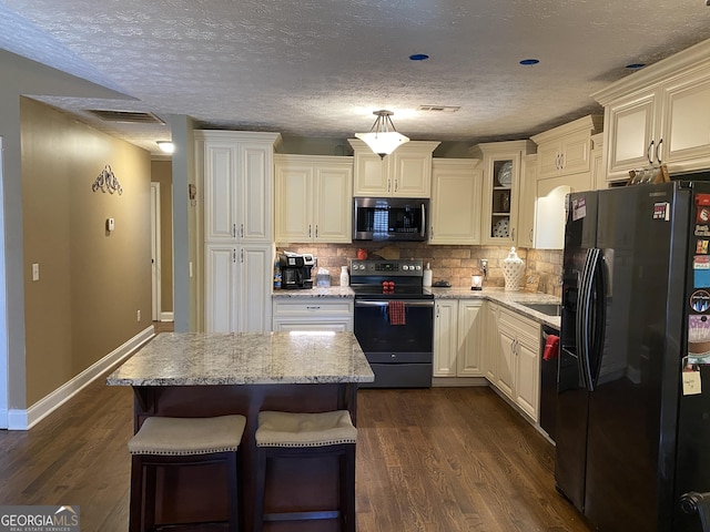 kitchen featuring light stone counters, dark hardwood / wood-style floors, a center island, and appliances with stainless steel finishes