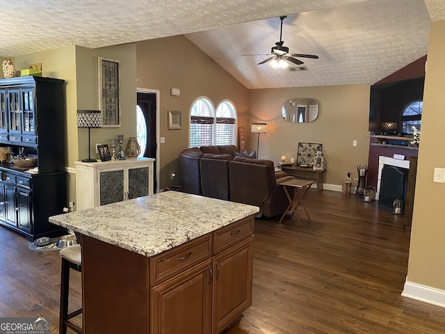 kitchen featuring lofted ceiling, dark hardwood / wood-style flooring, a center island, and a breakfast bar