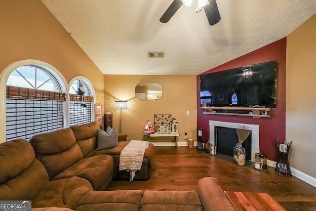 living room with wood-type flooring, lofted ceiling, ceiling fan, and a textured ceiling