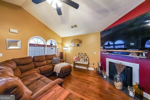 living room featuring lofted ceiling, ceiling fan, wood-type flooring, and a textured ceiling