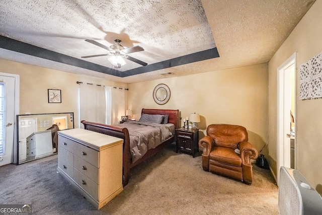 bedroom featuring ceiling fan, a raised ceiling, a textured ceiling, and carpet