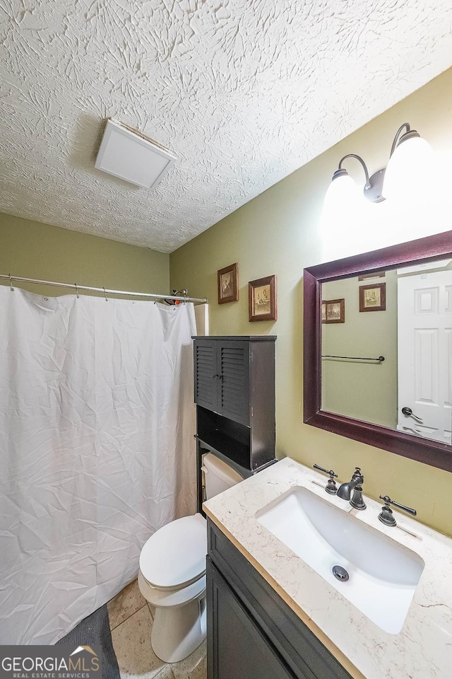 bathroom featuring tile patterned flooring, vanity, a textured ceiling, and toilet