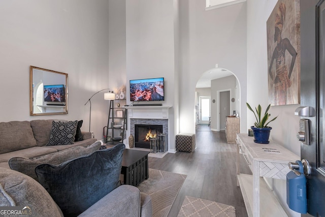 living room with dark hardwood / wood-style flooring, a fireplace, and a high ceiling